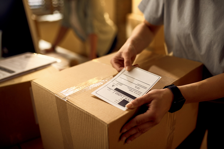 person placing shipping label on box
